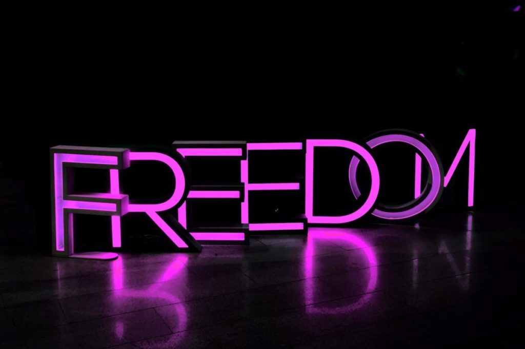 purple Freedom lighted freestanding letters on brown surface